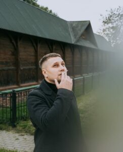 a man standing in front of a building smoking a cigarette